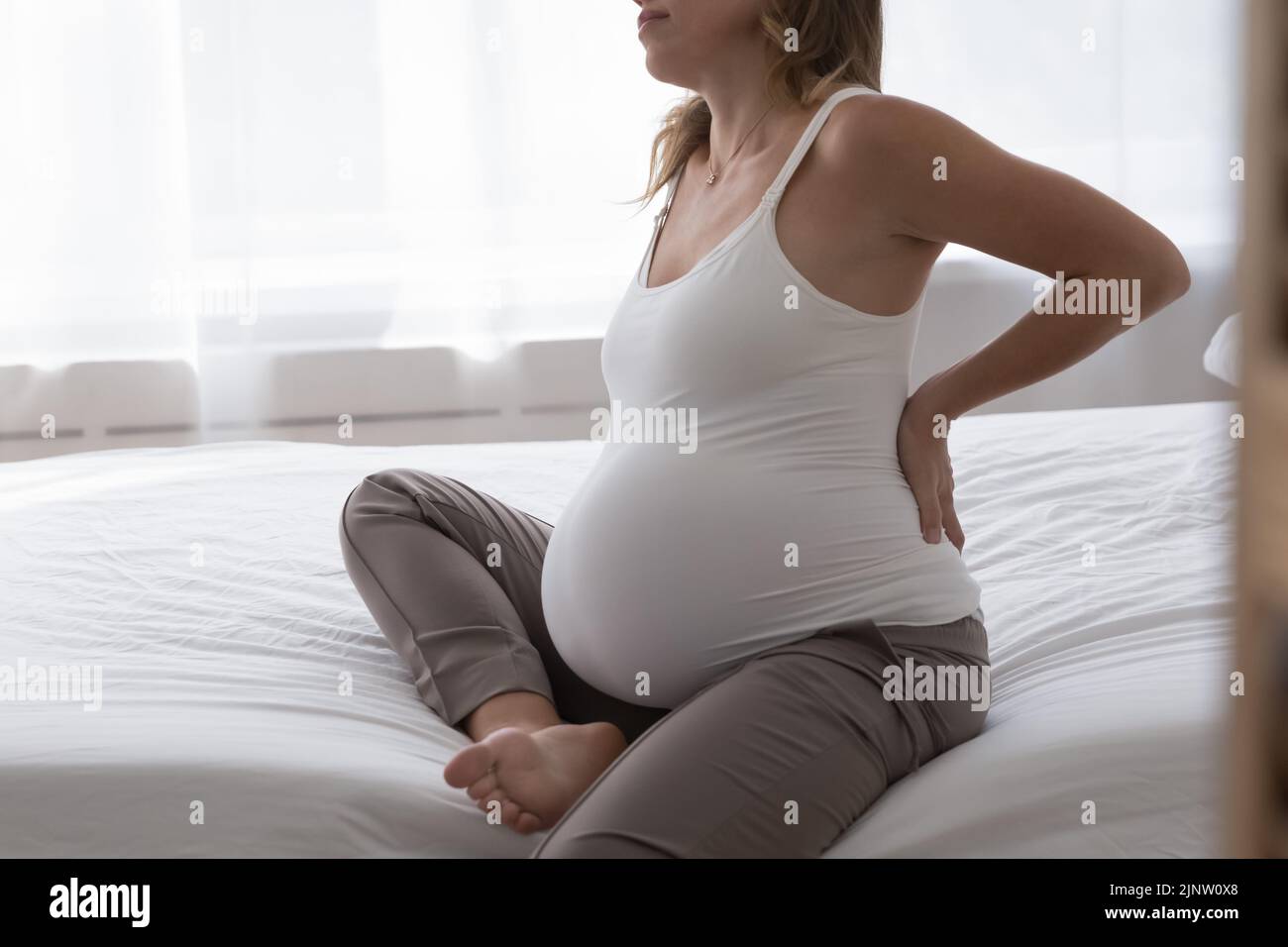 Pregnant woman touch her aching lower back, cropped shot Stock Photo