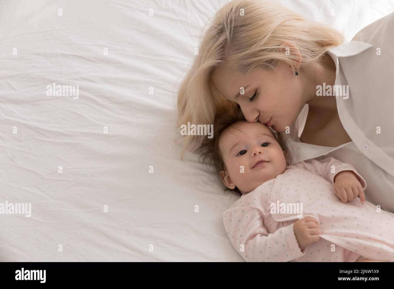 Young loving mother kisses on forehead her lovely newborn Stock Photo