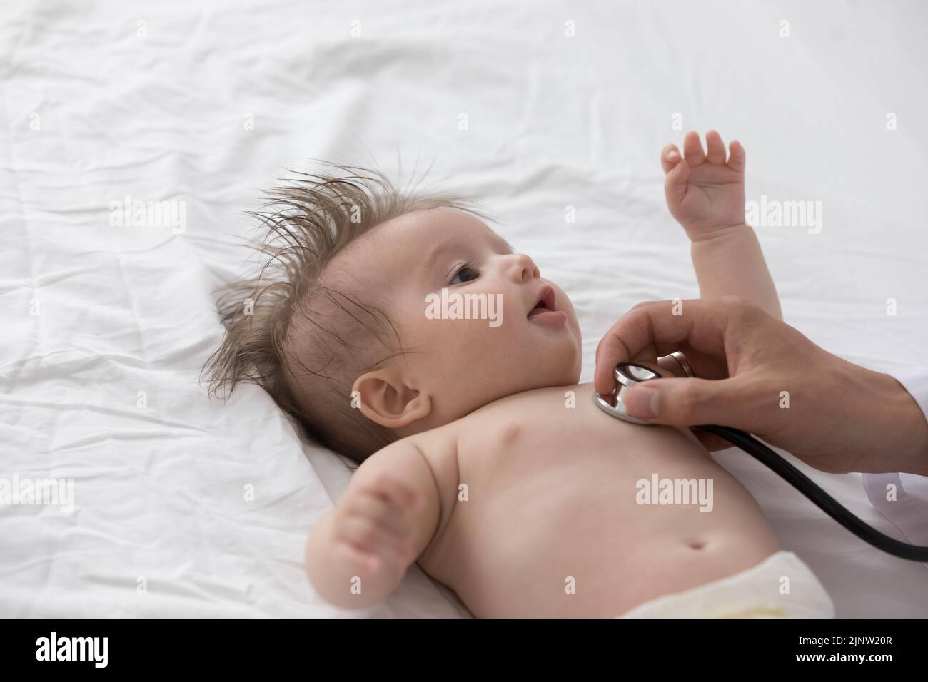 Pediatrician holds stethoscope listens newborn heartbeat, close up Stock Photo