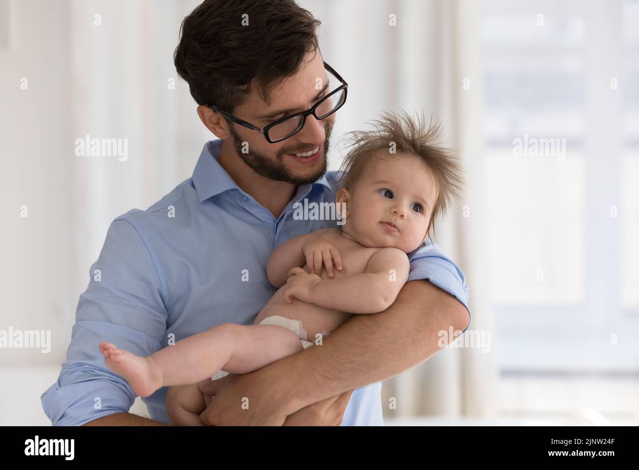 Young father cuddling his sweet newborn baby in diaper Stock Photo