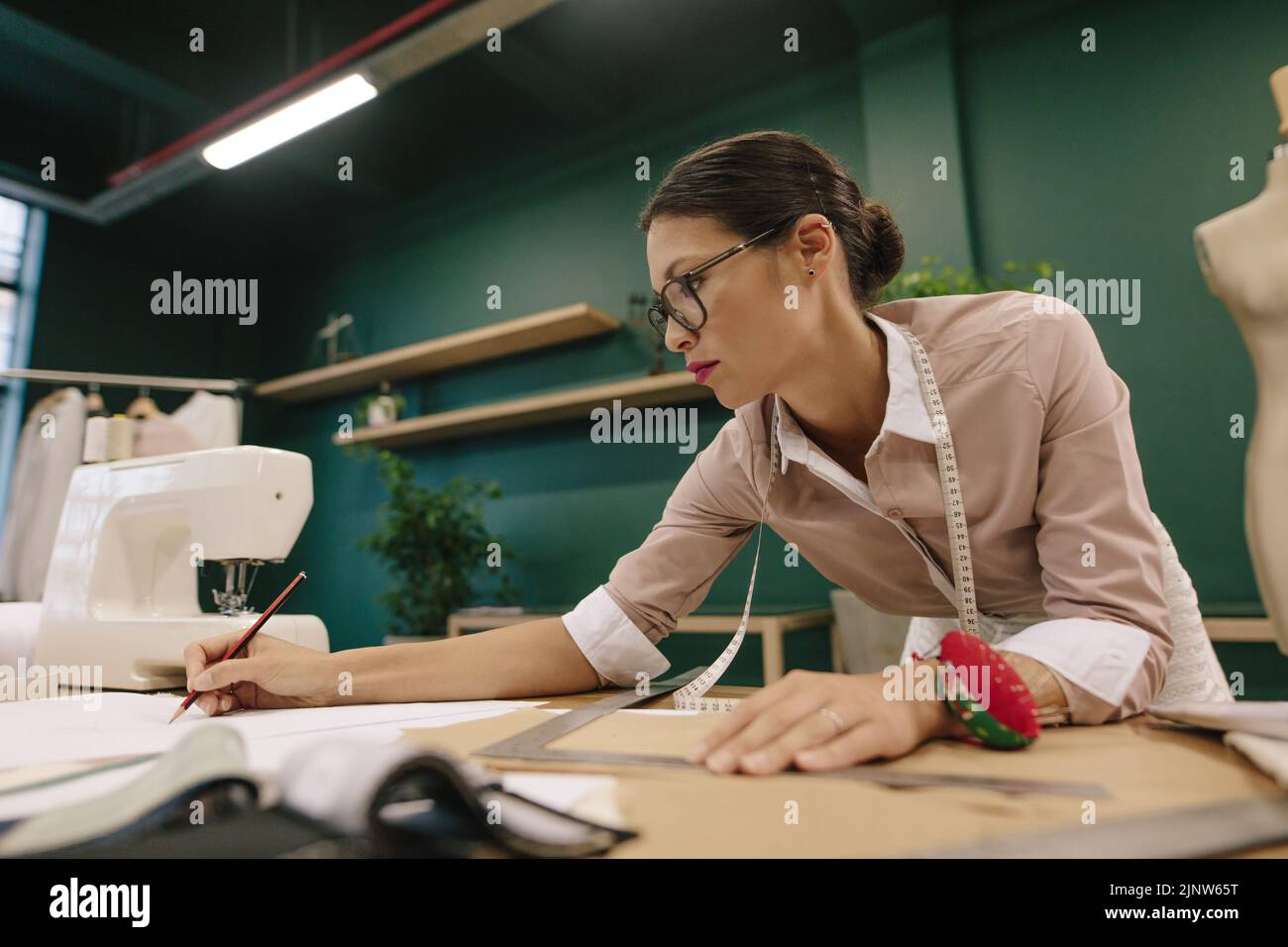 Fashion designer preparing design drafts on paper in the studio. Asian woman dressmaker working on table. Stock Photo