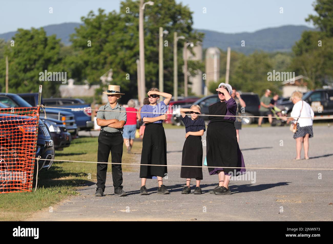 An Amish woman and children watch as workers reconstruct an 18th