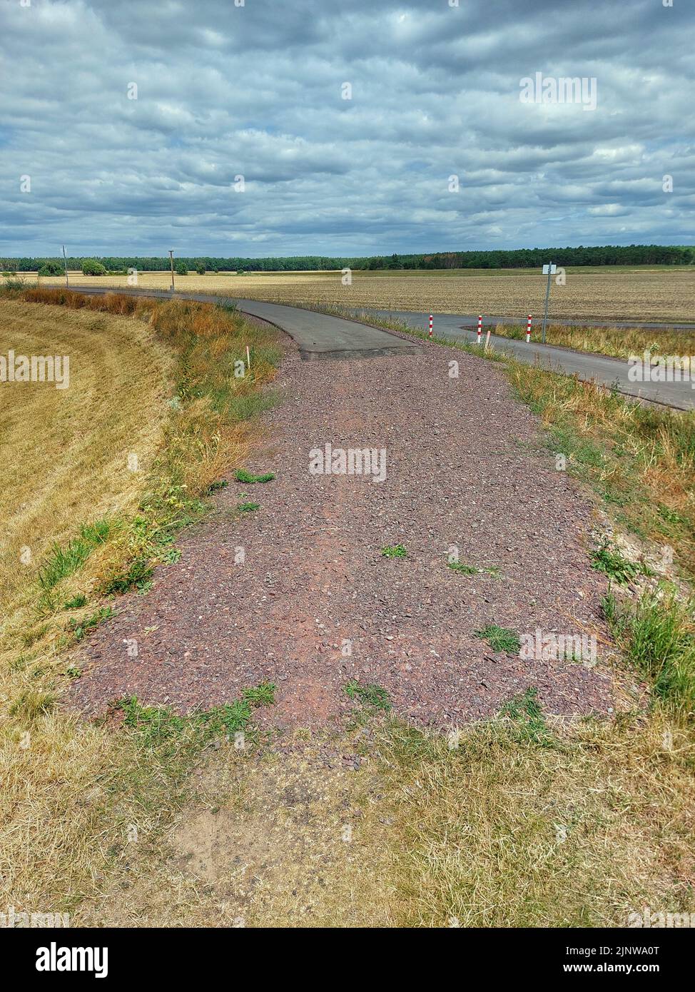 A small road ending in gravel and dirt road. Stock Photo