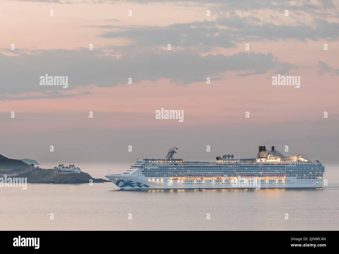 Cork Harbour, Cork, Ireland. 14th August, 2022. Cruise ship Island Princess about to  steam past the Roches Point Lighthouse at dawn on a cool summer's morning while on her way for a visit to Cobh, Co. Cork, Ireland.  - Picture David Creedon Stock Photo