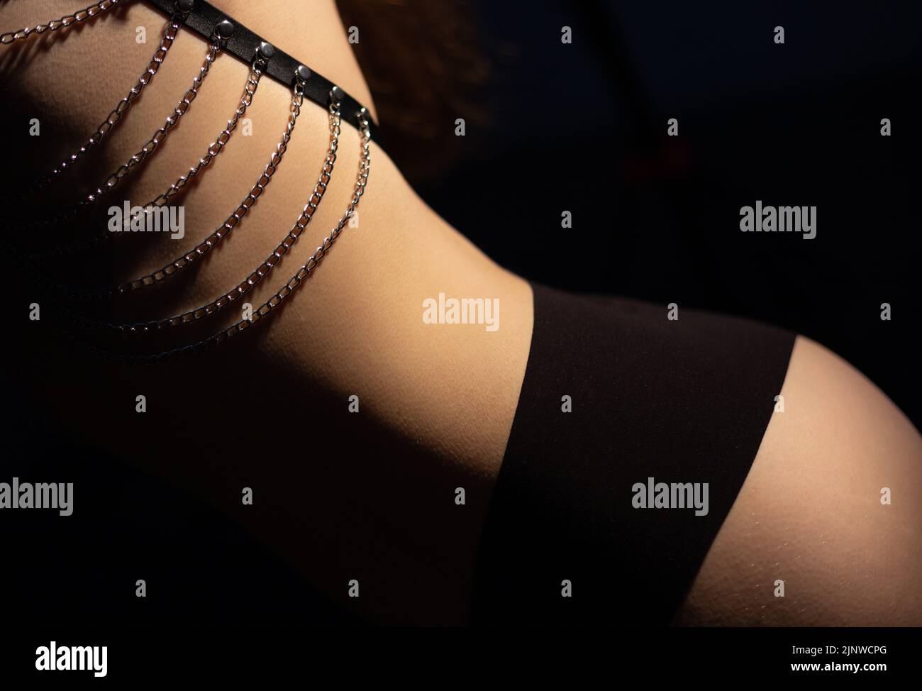 Image of woman in belt with hips wearing black lingerie in shadow Stock Photo