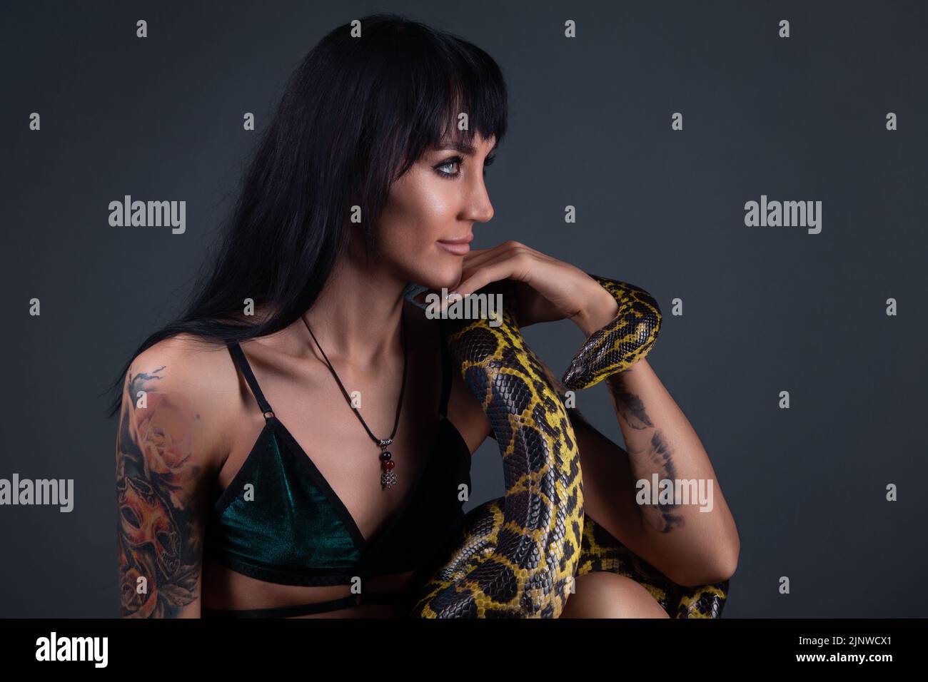 Photo of the brunette woman in profile sitting with yellow anaconda Stock Photo