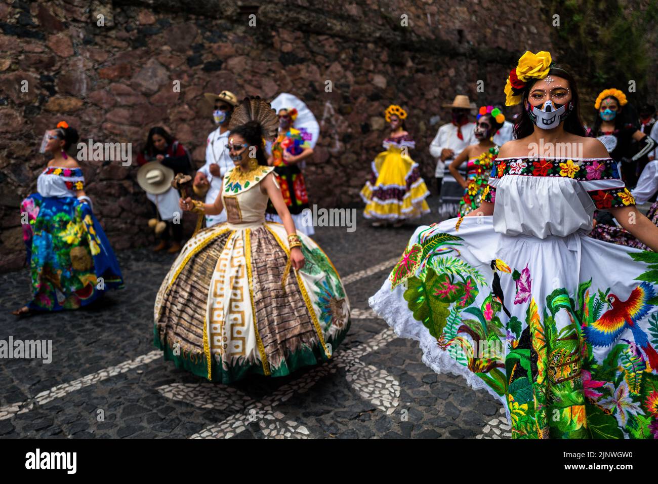 Mexican women, dressed as La Catrina, a Mexican pop culture icon representing the Death, dance in the Day of the Dead parade in Taxco, Mexico. Stock Photo