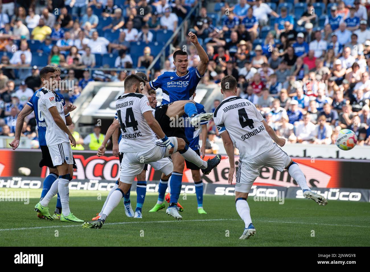 Bielefeld, Germany. 13th Aug, 2022. Soccer: 2. Bundesliga, Arminia Bielefeld - Hamburger SV, Matchday 4, Schüco Arena. Bielefeld's Frederik Jäkel shoots at goal. Hamburg's Sebastian Schonlau is on the right. Credit: Swen Pförtner/dpa - IMPORTANT NOTE: In accordance with the requirements of the DFL Deutsche Fußball Liga and the DFB Deutscher Fußball-Bund, it is prohibited to use or have used photographs taken in the stadium and/or of the match in the form of sequence pictures and/or video-like photo series./dpa/Alamy Live News Stock Photo