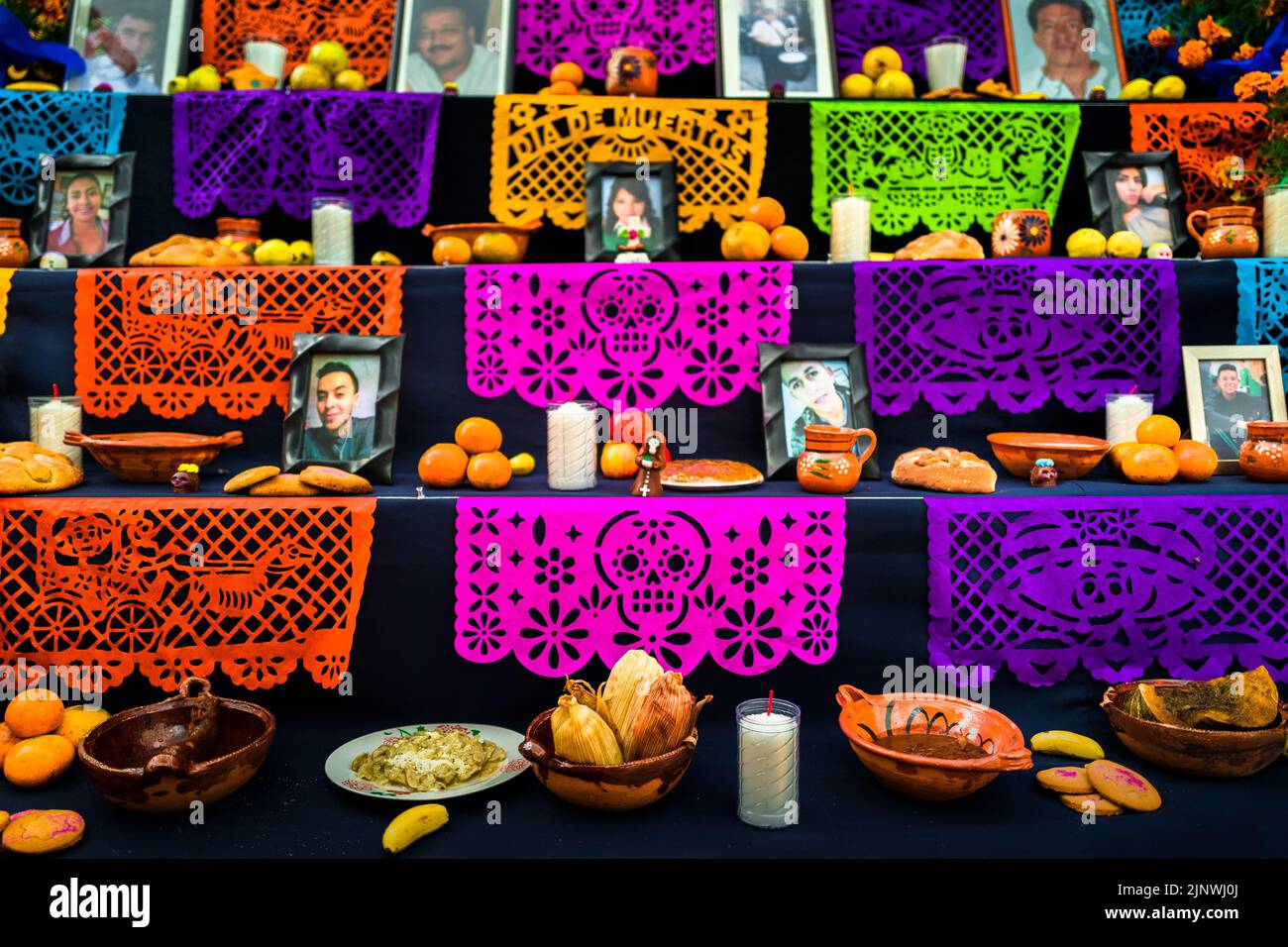 Food offerings and pecked paper flags are placed at the altar of the dead during the Day of the Dead celebrations in Taxco de Alarcón, Mexico. Stock Photo