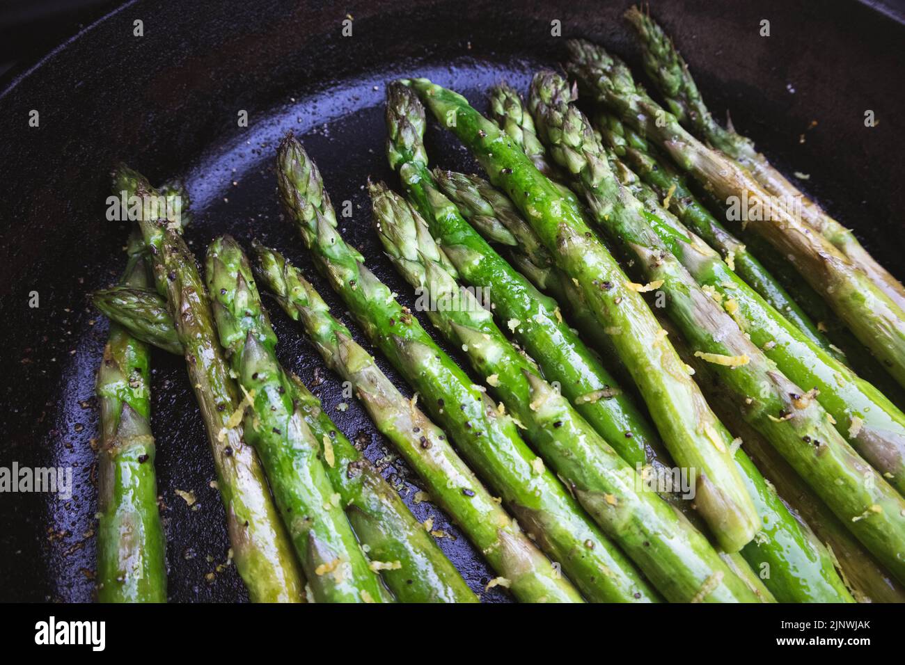 Asparagus with lemon zest grilled outdoors in a cast iron skillet Stock