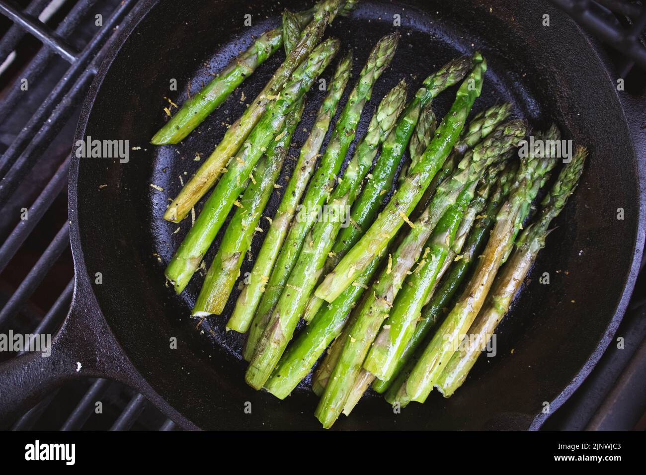 Asparagus with lemon zest grilled outdoors in a cast iron skillet Stock Photo