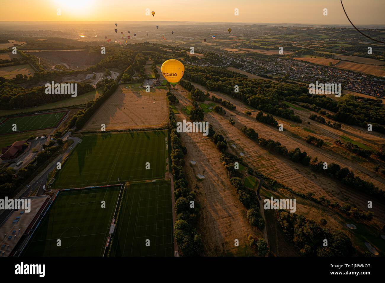 A hot air balloon flies over a browning and parched golf course early in the morning, as a drought has been declared for parts of England following the driest summer for 50 years. Picture date: Sunday August 14, 2022. Stock Photo