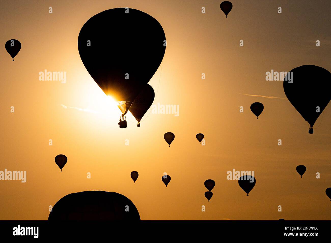 A hot air balloons pass by the sun as they fly over North Somerset in early morning sunlight, during the mass ascent the Bristol International Balloon Fiesta 2022. Picture date: Sunday August 14, 2022. Stock Photo