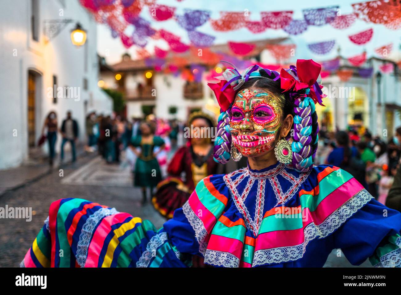 A Mexican girl, dressed as La Catrina, a Mexican pop culture icon representing the Death, dances in the Day of the Dead parade in Taxco, Mexico. Stock Photo