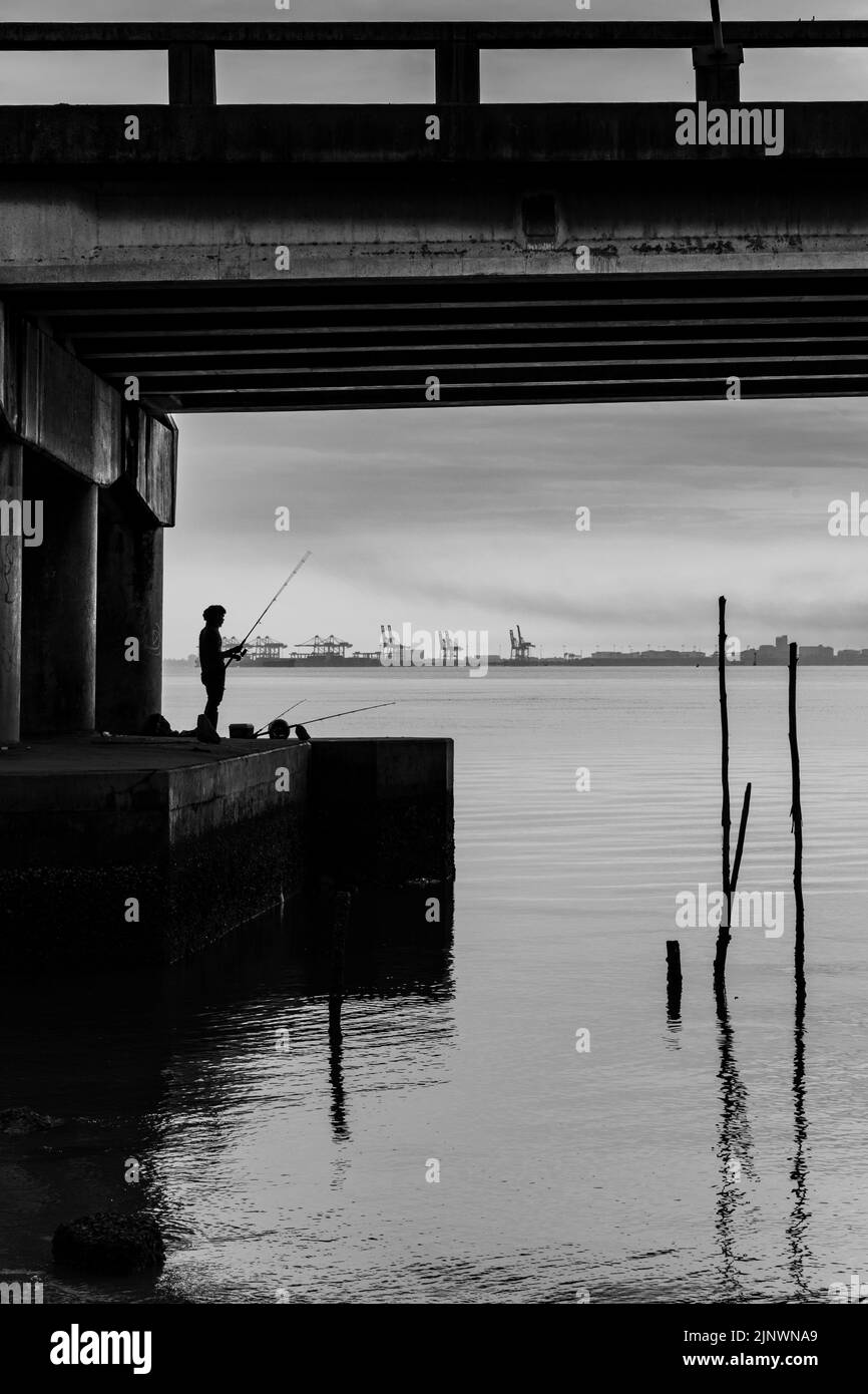 Sunrise shoot under the Penang Bridge. Fisherman fishing under the bridge. Penang bridges are crossings over the Penang Strait in Malaysia. Stock Photo