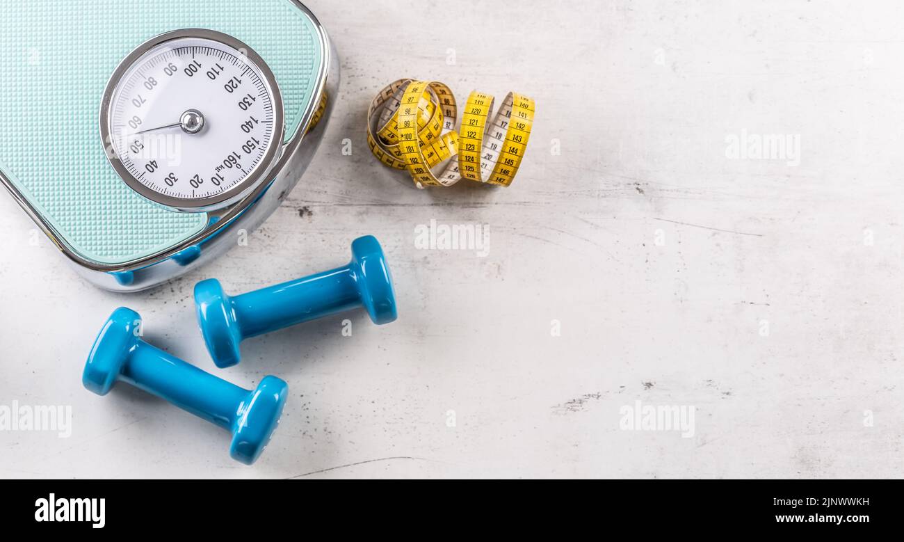 Weight scale and dumbbells with measure tape on floor - Top of view. Stock Photo