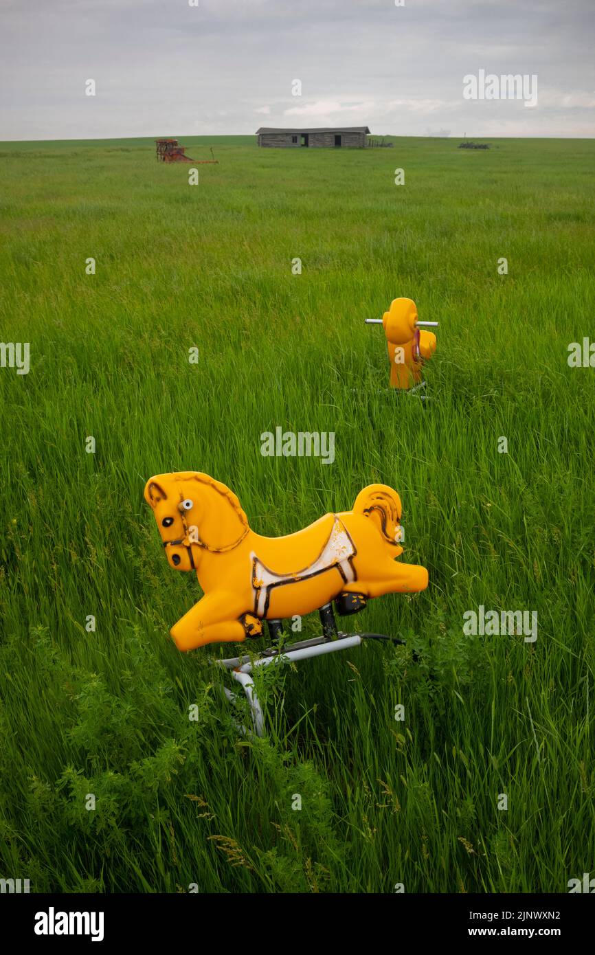 Two rocking-horses sit dormant in a vast grassland in North Dakota during an overcast day. Stock Photo