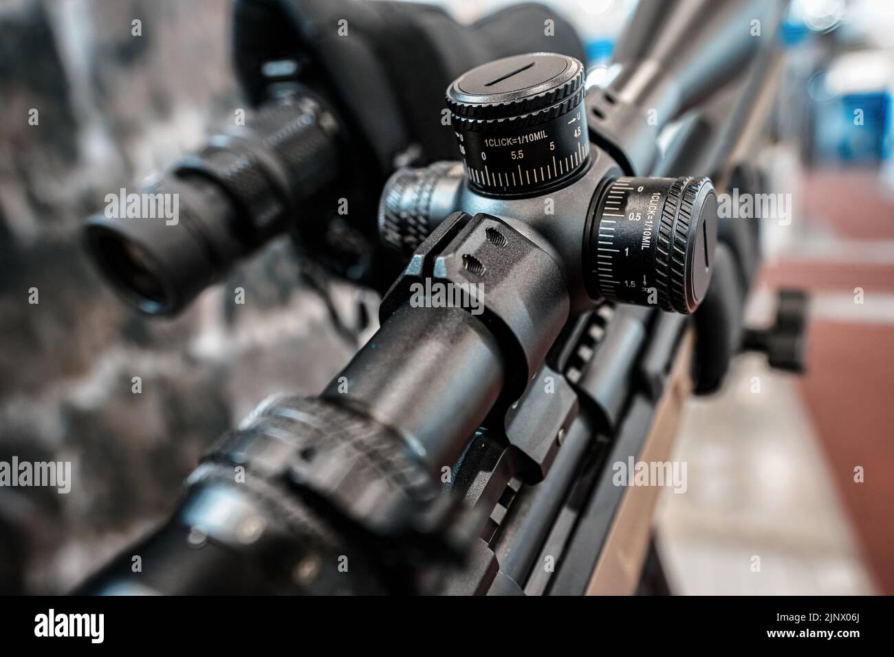 Black shooting scope optics mounted on rifle displayed at weapons exhibition fair, closeup detail to adjustment knobs Stock Photo
