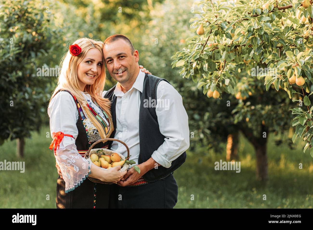 Young couple in Serbian traditional holding a basket with fresh pears Stock Photo