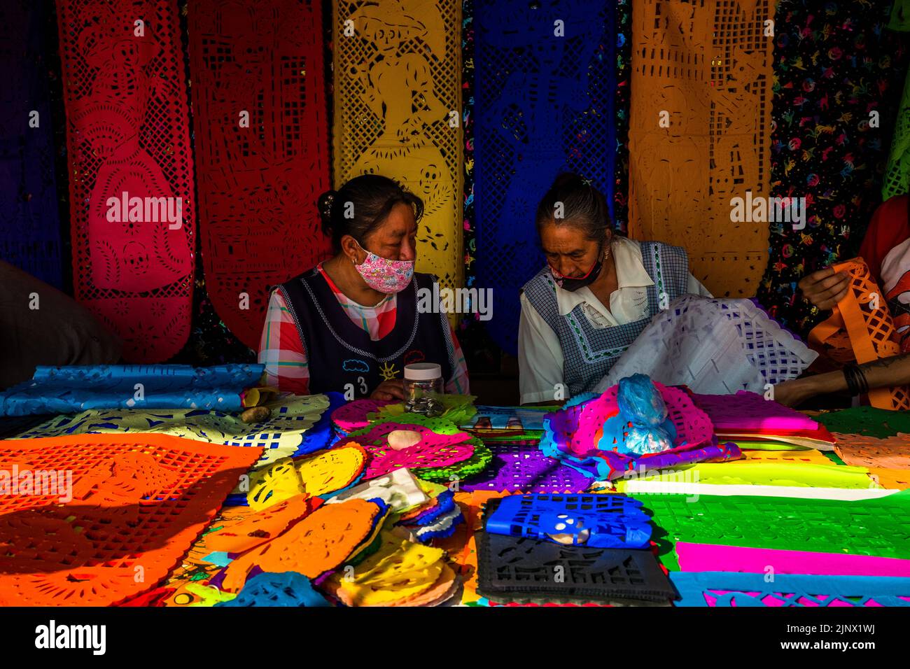 Mexican indigenous women sell chiseled paper flags for the Day of the Dead celebrations on the market in Xochimilco, Mexico City, Mexico. Stock Photo