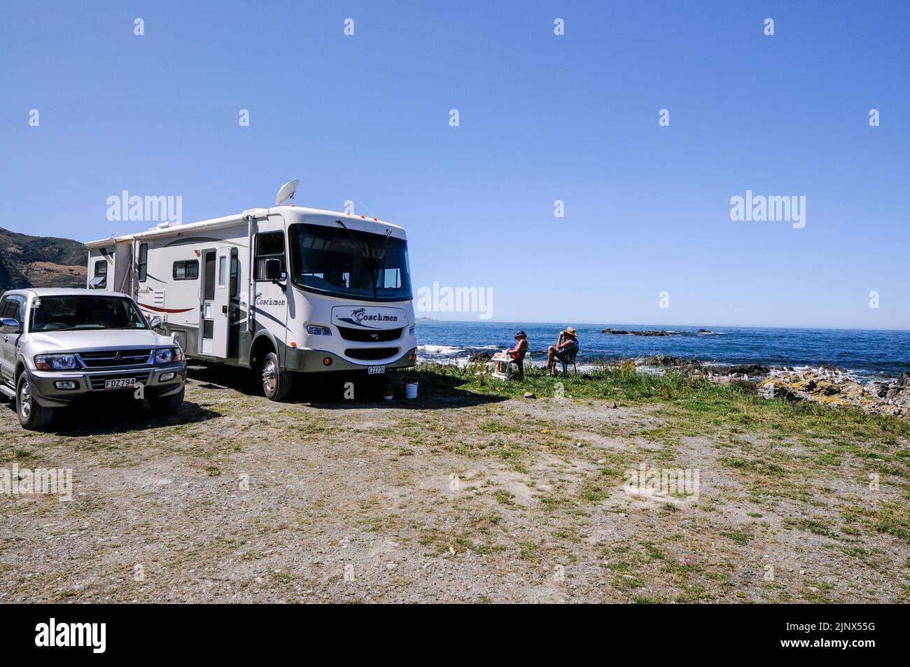 Campers relaxing on a beach facing the Pacific Ocean in Kaikoura on New Zealand's south island Stock Photo