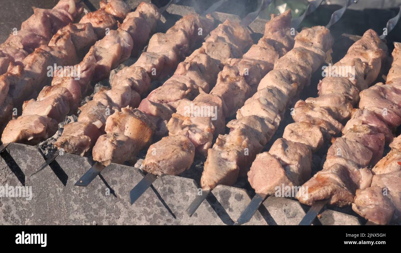 Process of cooking yummy shashlik in nature. Delicious food on metal skewer in bbq.  Kebab - street food. Food festival. Grilling tasty dish on barbec Stock Photo
