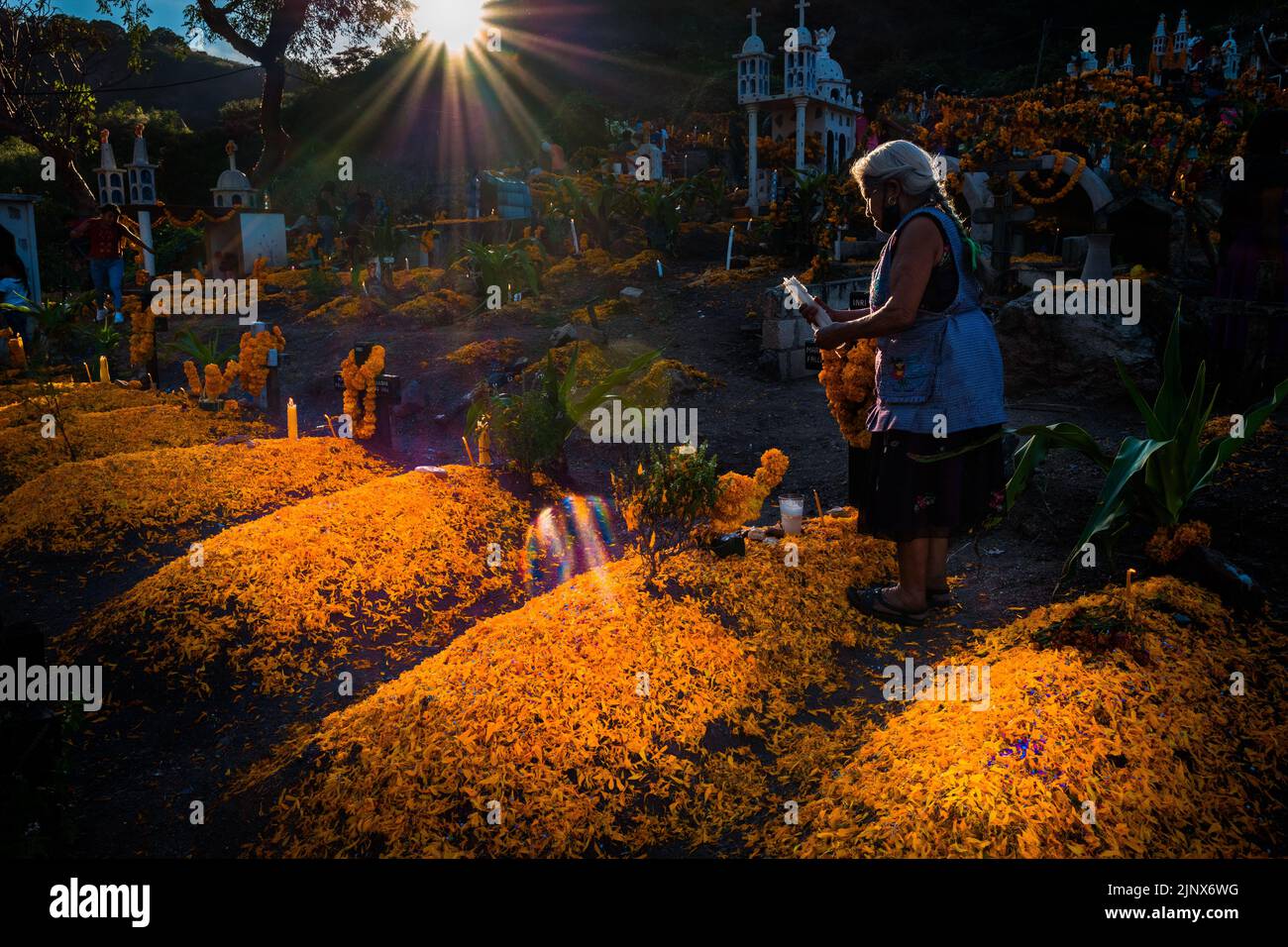 A Mixtec indigenous woman decorates a gravesite at a cemetery during the Day of the Dead celebrations in Xalpatláhuac, Mexico. Stock Photo