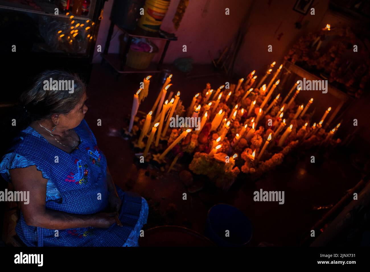 A Mixtec indigenous woman sits in front of an altar of the dead (Altar de Muertos) during the Day of the Dead celebrations in Metlatónoc, Mexico. Stock Photo