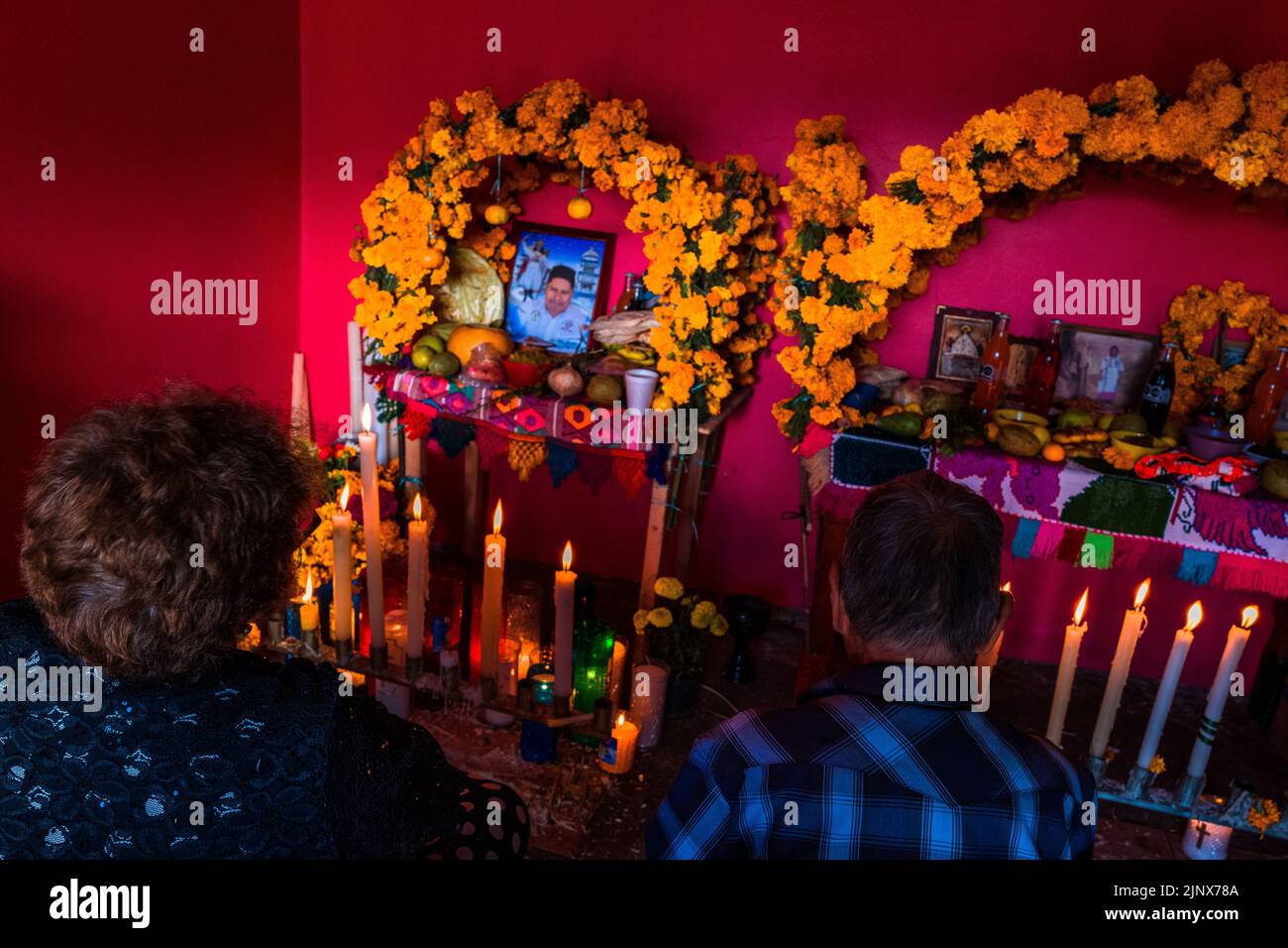 A Mexican couple sits in front of an altar of the dead (Altar de Muertos) during the Day of the Dead celebrations in Metlatónoc, Guerrero, Mexico. Stock Photo