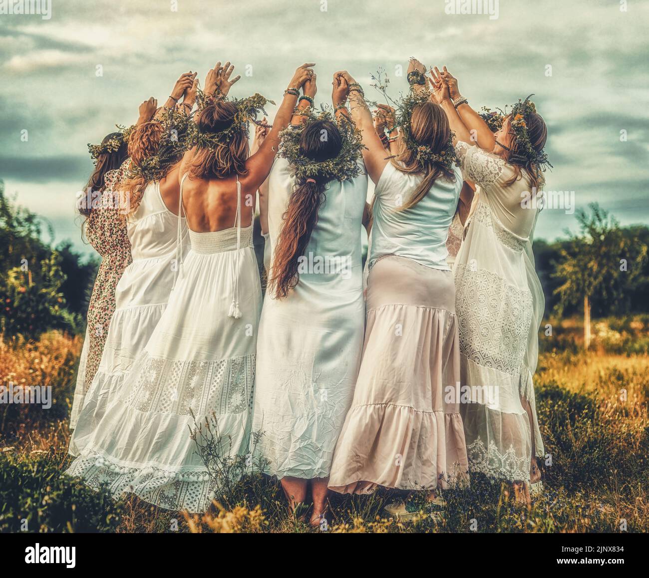 Women in flower wreath on sunny meadow, Floral crown, symbol of summer solstice. Stock Photo