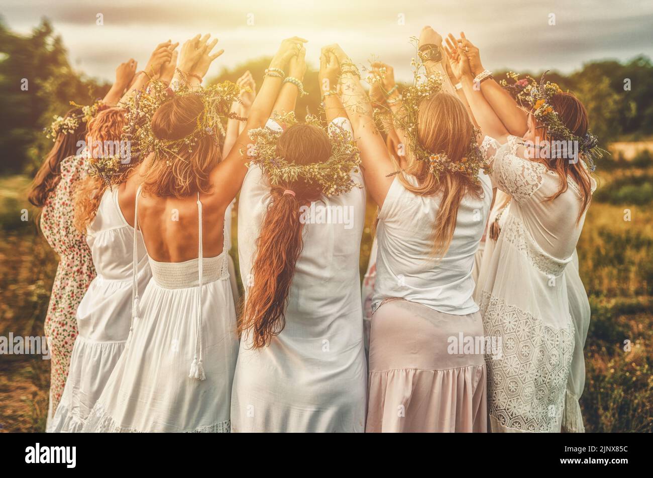Women in flower wreath on sunny meadow, Floral crown, symbol of summer solstice. Stock Photo