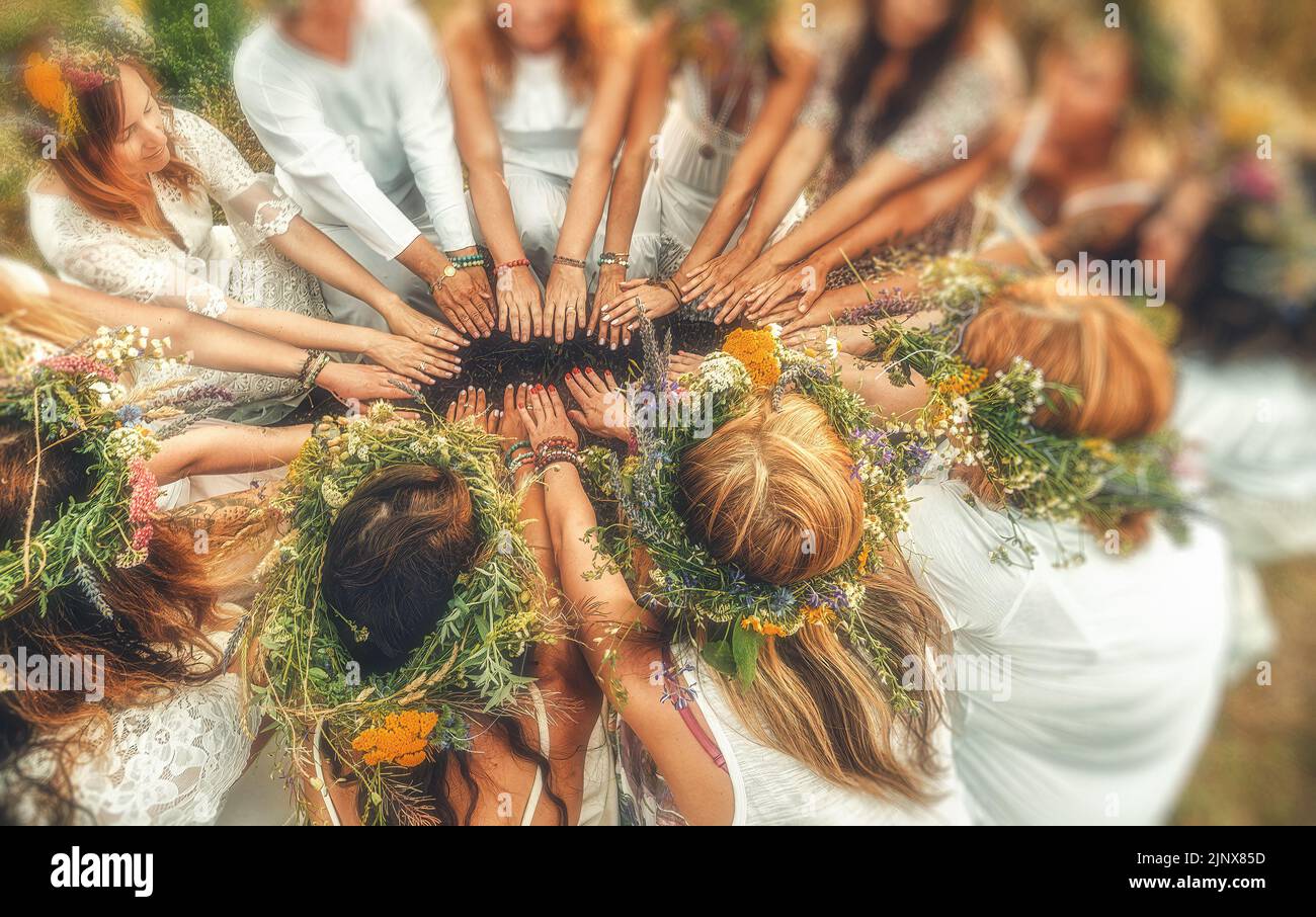 Women in flower wreath on sunny meadow, Floral crown, symbol of summer solstice. Stock Photo