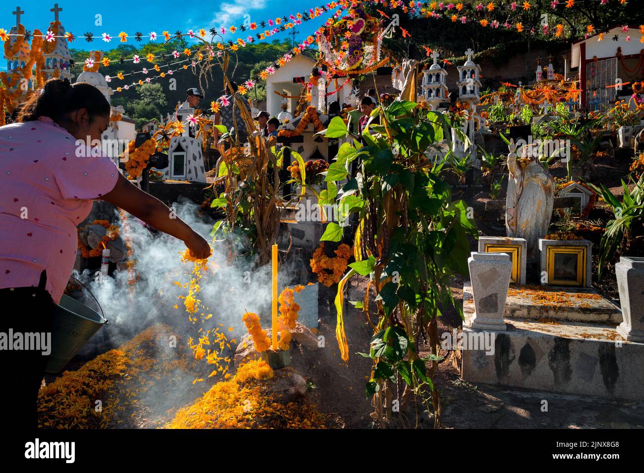 A Mixtec indigenous woman decorates a gravesite at a cemetery during the Day of the Dead celebrations in Xalpatláhuac, Guerrero, Mexico. Stock Photo