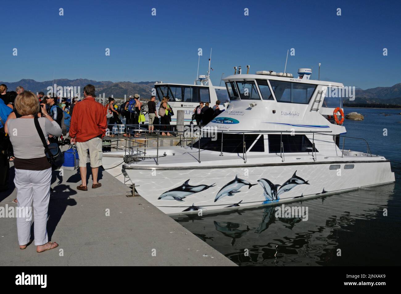 Tourists gather on the quay waiting to board the two Dolphin Watch boats near the town of Kaikoura on the east coast of South Island in New Zealand. Stock Photo