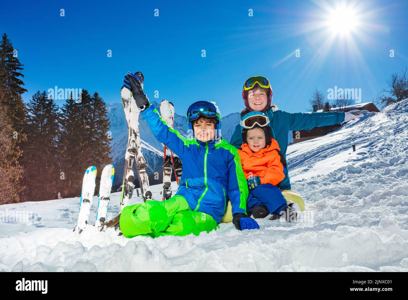 Two kids and mother on ski vacation sit together in the snow Stock Photo