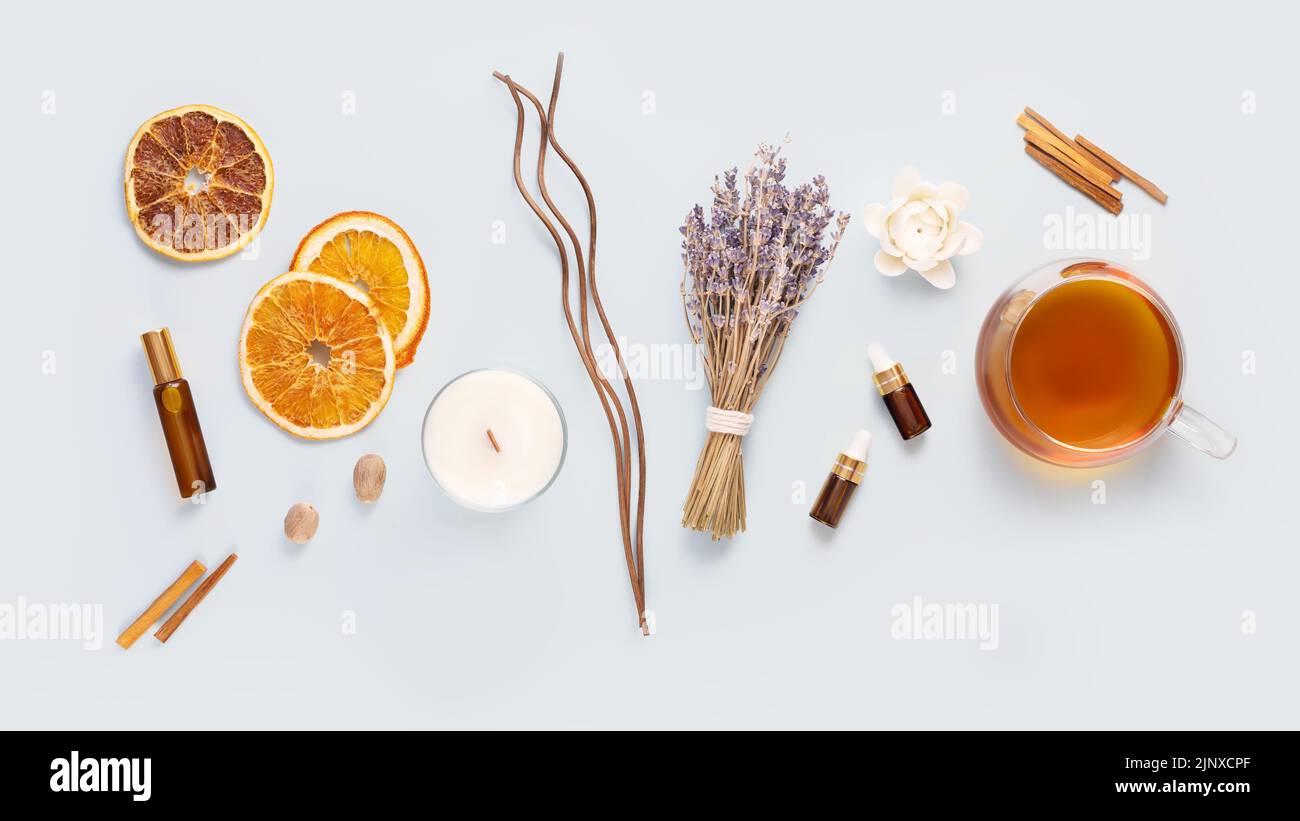 Relax at home. Cup of herbal tea, aroma candle, sticks, lavender flowers, dry orange slices and natural oils on a blue background. Insomnia or depress Stock Photo