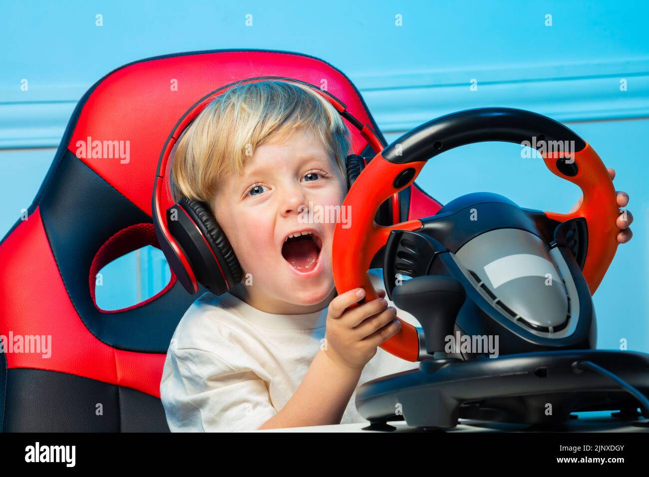 Little boy in headphones with steering wheel play race game Stock Photo