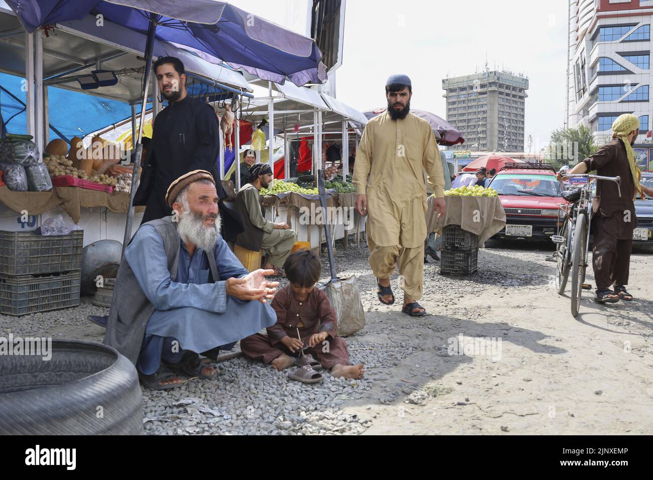 A man (L) and a child sitting on the ground beg in Kabul on Aug. 14, 2022. (Kyodo)==Kyodo  Photo via Newscom Stock Photo