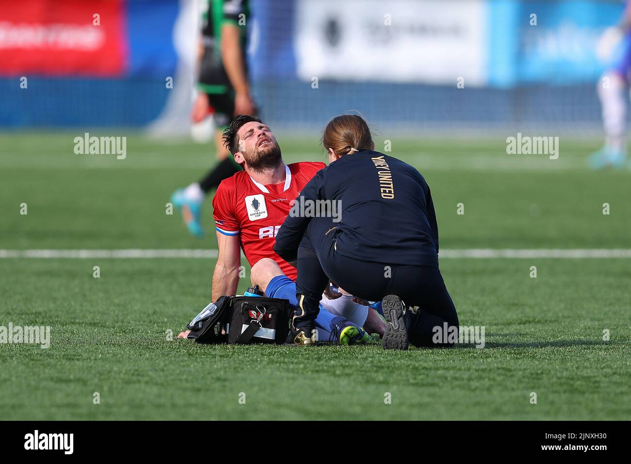 14 August 2022, Sydney United Sports Centre, Sydney Australia: Australia Cup Sydney United 58 FC  versus Western United: Chris Payne of Sydney United 58 FC receives medical treatment to an injury to his left leg Stock Photo
