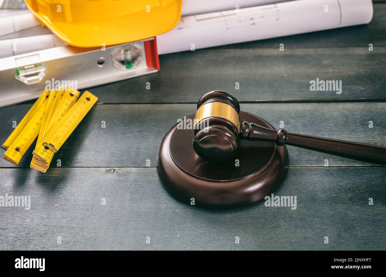 Construction and Labor law. Judge gavel and building drawings on wooden table, close up view. Stock Photo