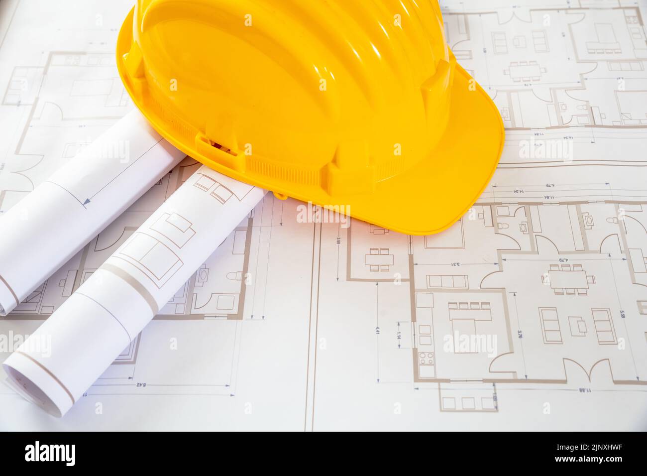 Construction project. Yellow safety helmet and building blueprint plans, copy space. Architect engineer office Stock Photo