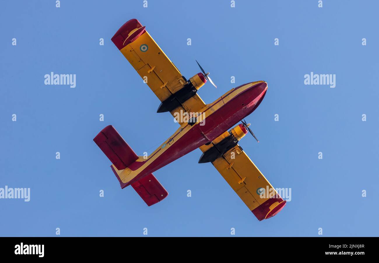 Canadair flight, Amphibious Firefighting Aircraft, Scooper on clear blue sky background. Yellow red color contemporary seaplane for firefight, search, Stock Photo