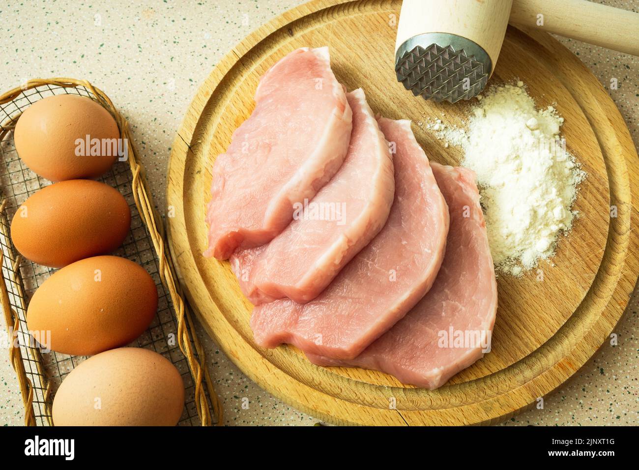 Sliced pork loin on a board, flour and eggs, top view Stock Photo