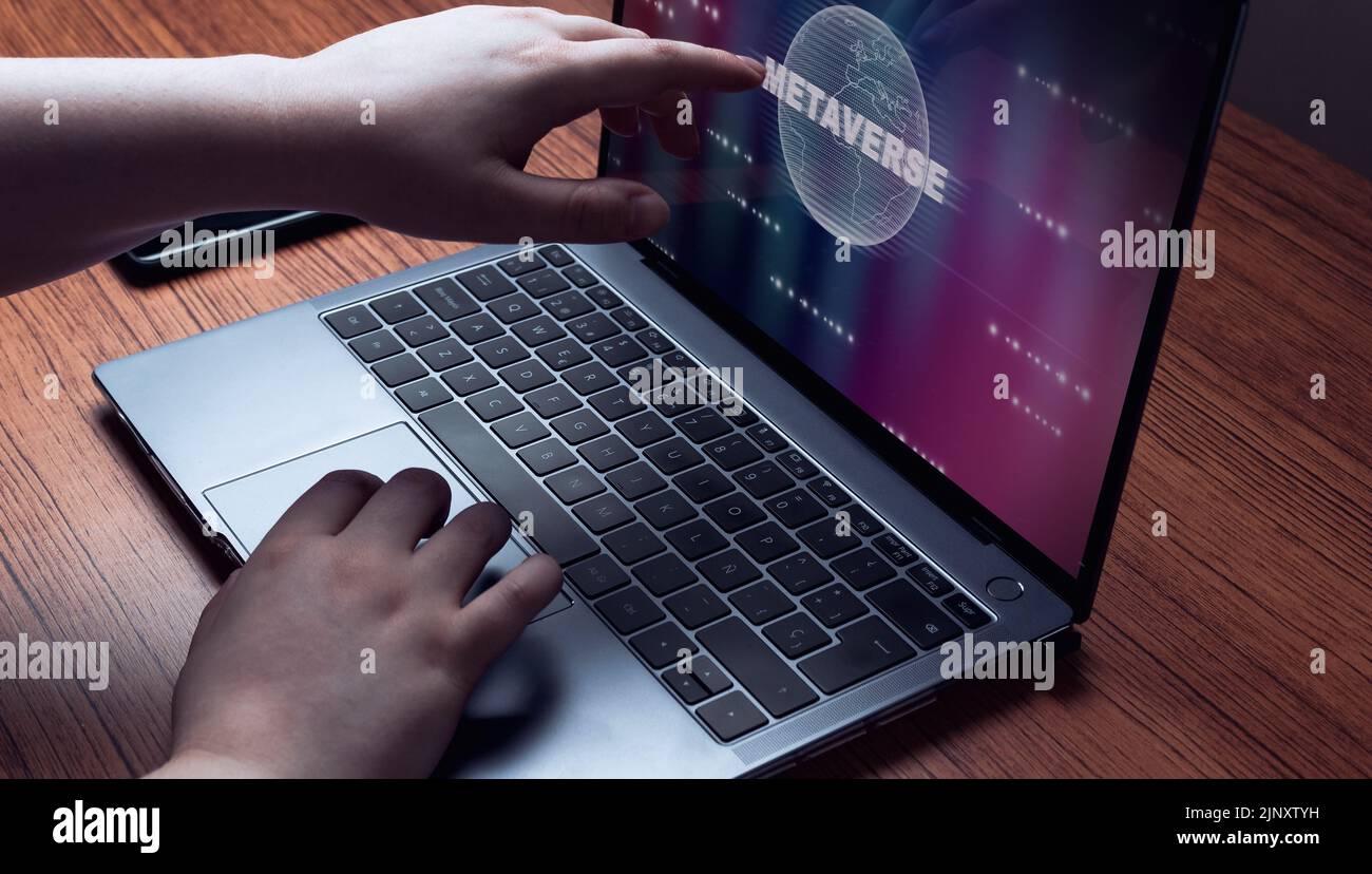 Woman touching laptop screen with metaverse hologram to log in. Technology and digital marketing. Digital link tech. Big data. Stock Photo