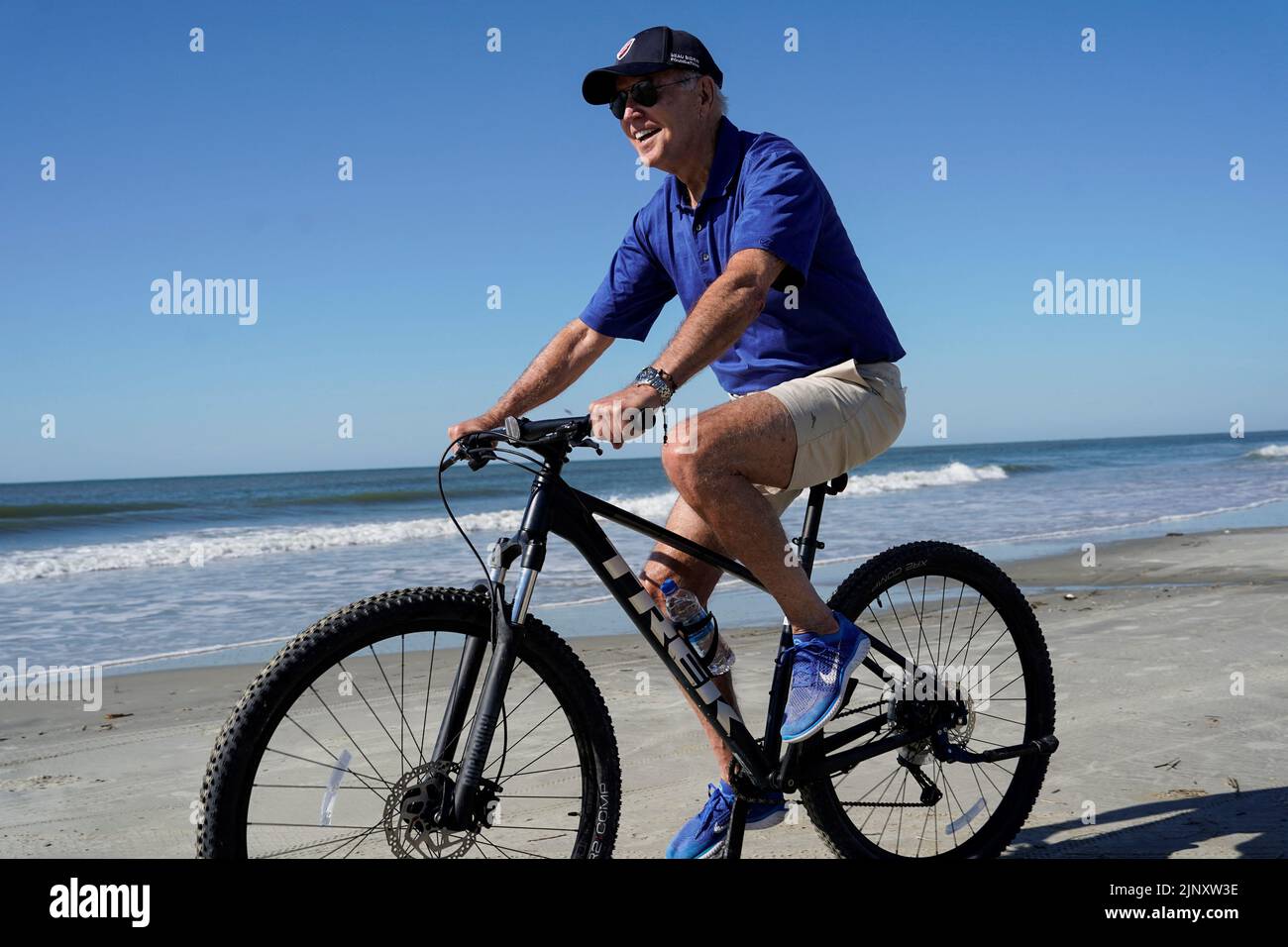U.S. President Joe Biden rides a bicycle on the beach on Kiawah Island, South Carolina, U.S., August 14, 2022. REUTERS/Joshua Roberts Stock Photo