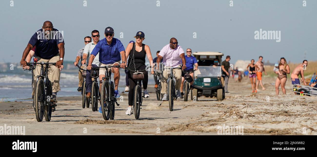 U.S. President Joe Biden rides a bicycle with Secret Service agents on the beach on Kiawah Island, South Carolina, U.S., August 14, 2022.  REUTERS/Joshua Roberts Stock Photo