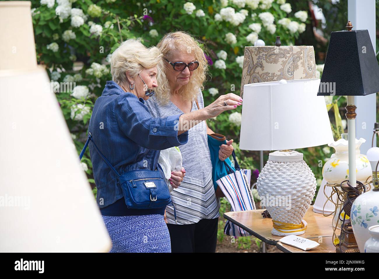 Two women examine a lamp at a church flea market in Dennis