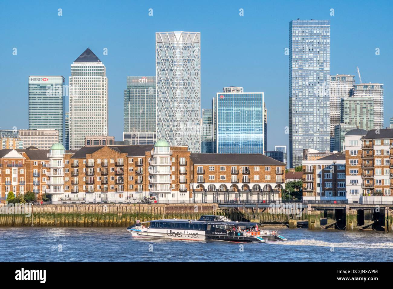An Uber Boat by Thames Clippers passing the Rotherhithe Peninsula with Canary Wharf & the Isle of Dogs in the background. Stock Photo