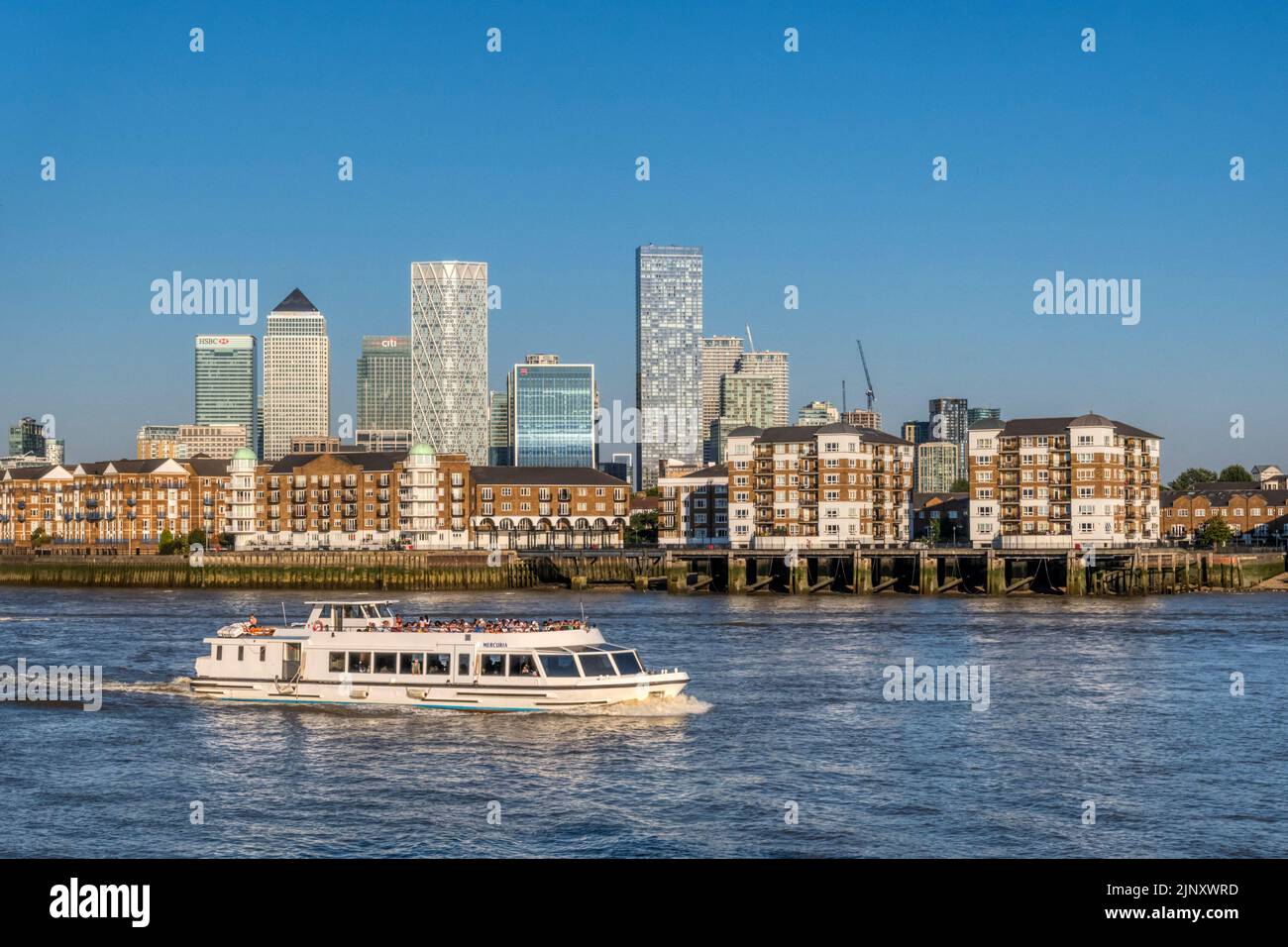 Sightseeing boat Mercuria passing the Rotherhithe Peninsula with Canary Wharf & the Isle of Dogs in the background. Stock Photo