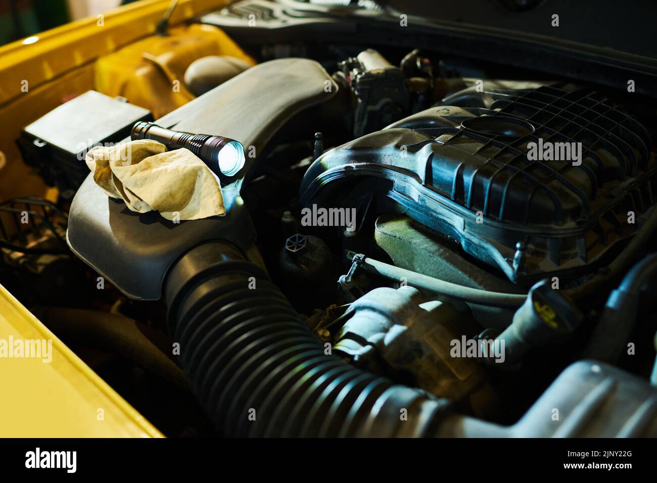 Part of engine of electric car with flashlight for check up work and duster for wiping dirty details of motor in open hood Stock Photo